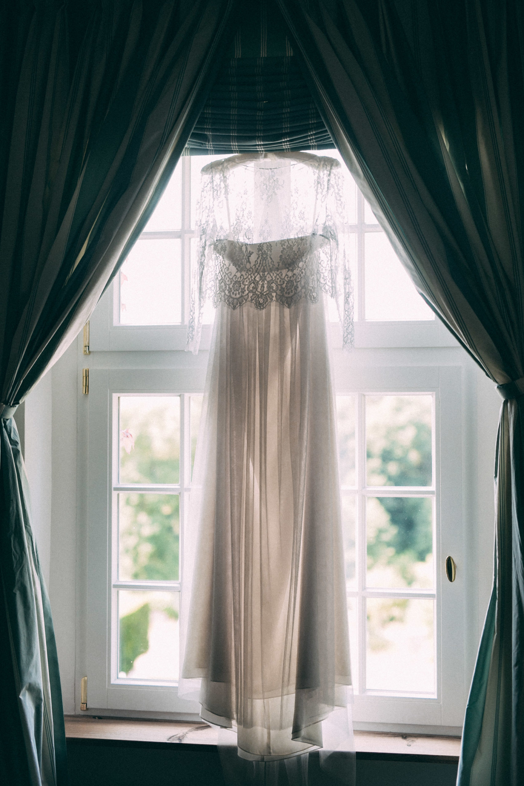 Hochzeitskleid hängt im Fenster und wird fotografiert