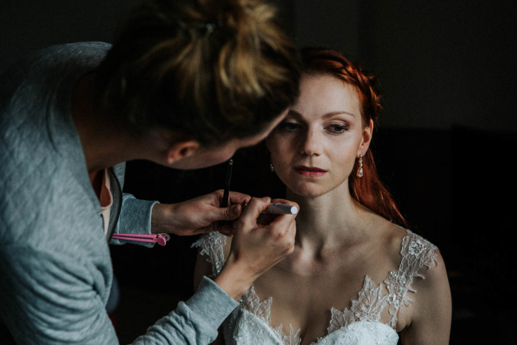 Visagistin schminkt die Braut bei einer Hochzeit